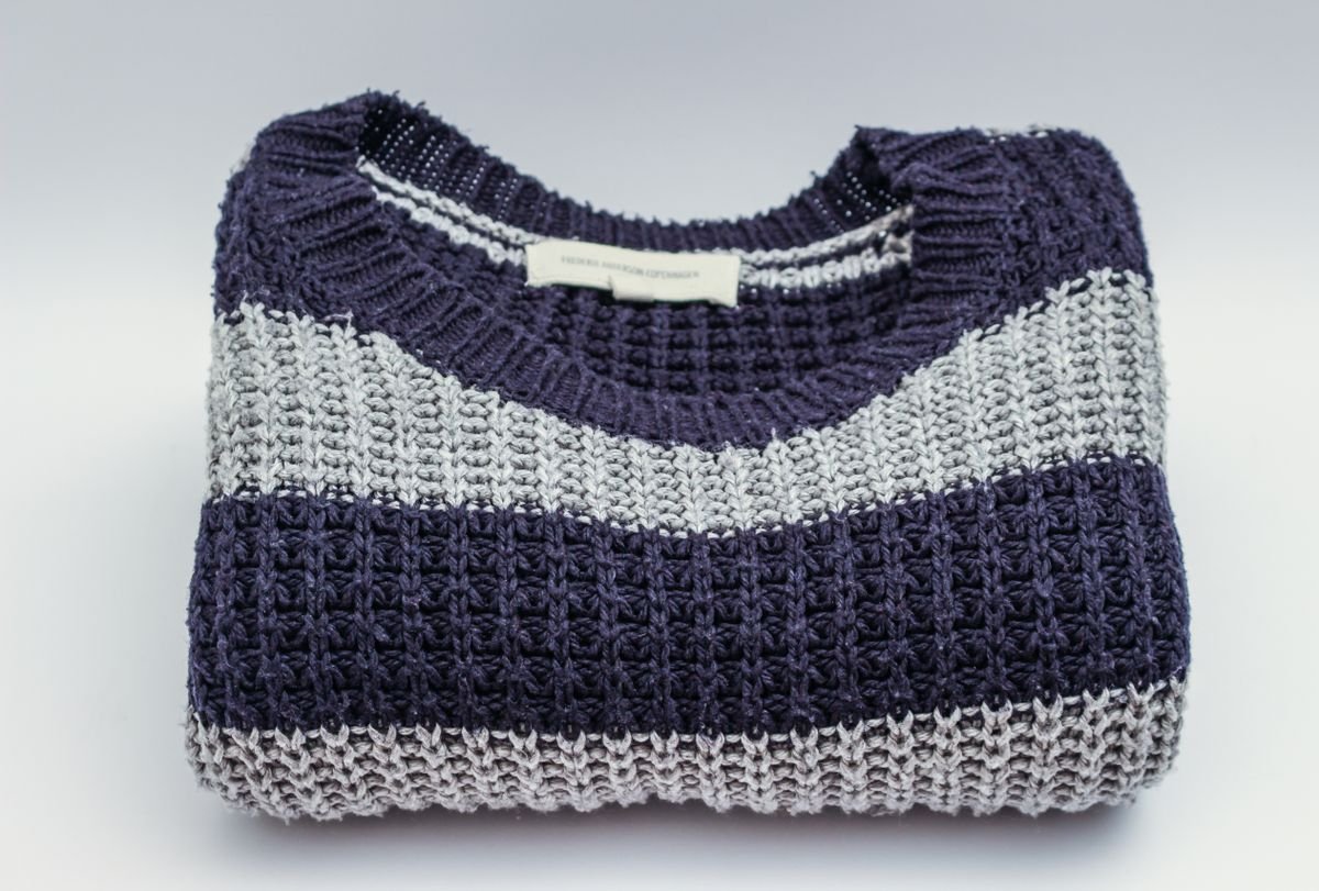 A folded navy and grey wool knit jumper