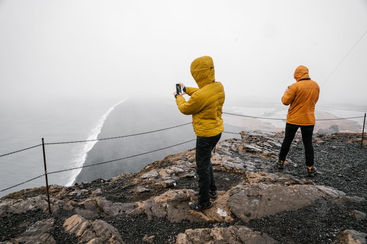 Two walkers in waterproof jackets on a misty Irish clifftop