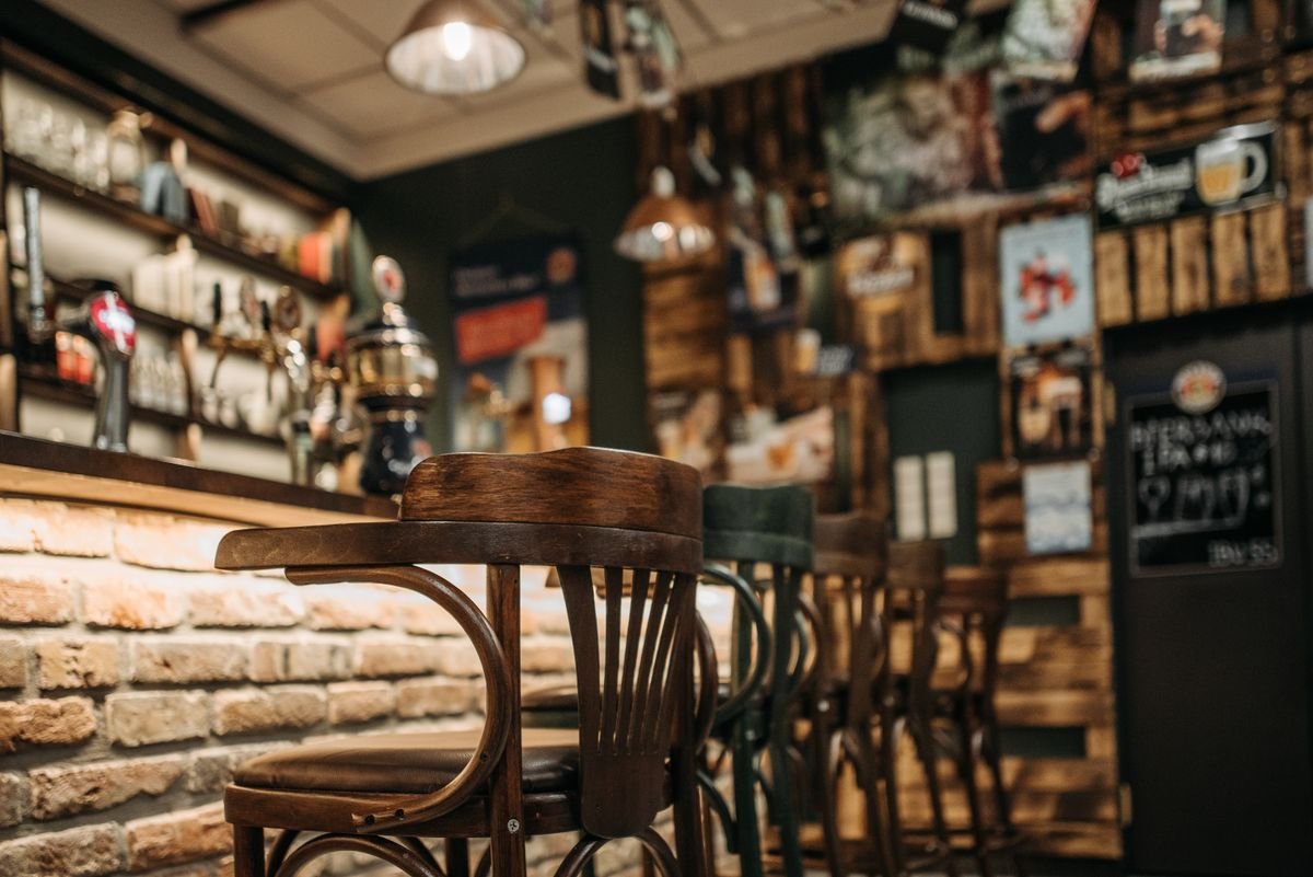 Inside a traditional Irish pub: brass-railed bar stools, a tiled floor, and a wall of whiskey behind the bar.