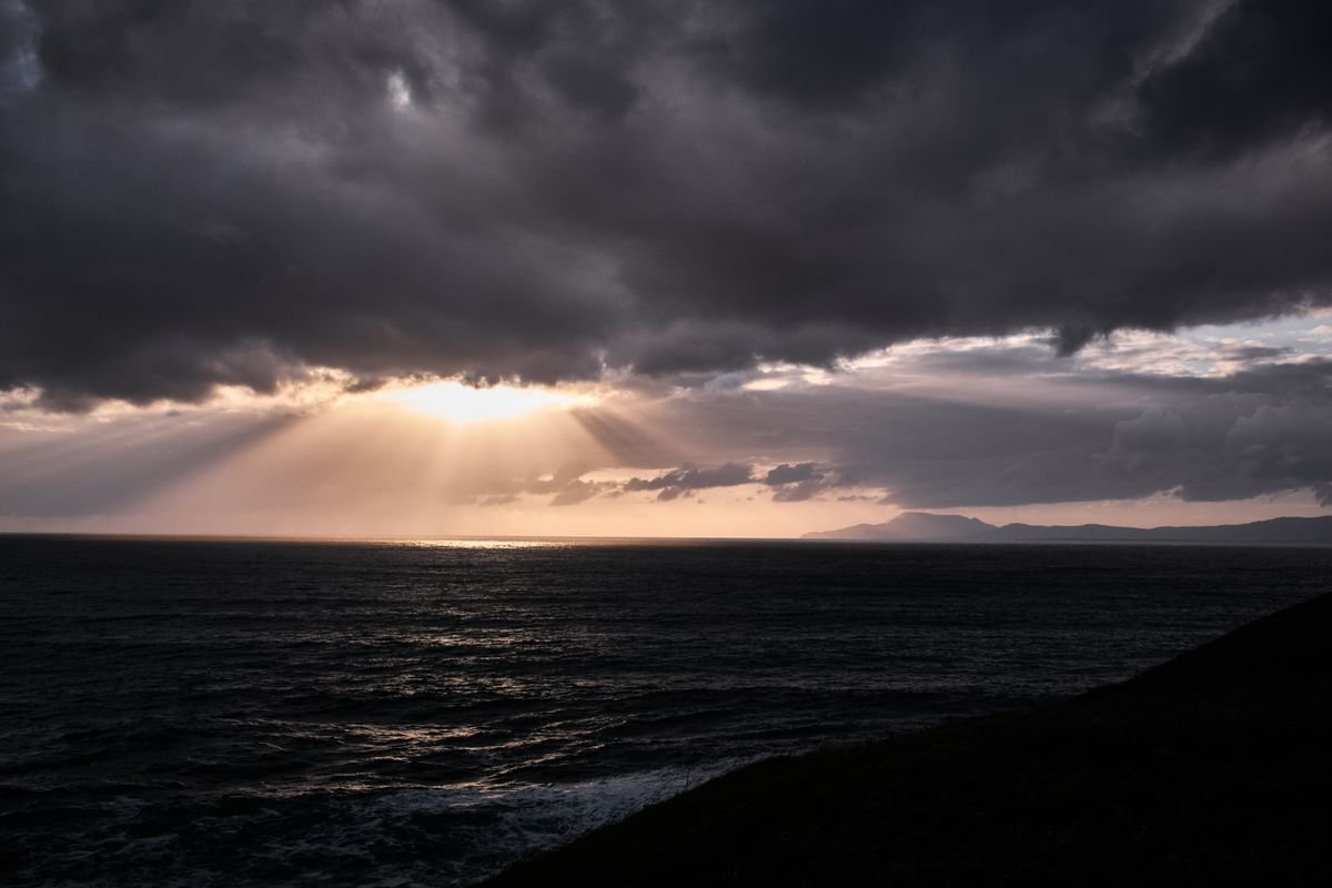 Sun breaking through brooding clouds over the Atlantic off the Donegal coast at dusk