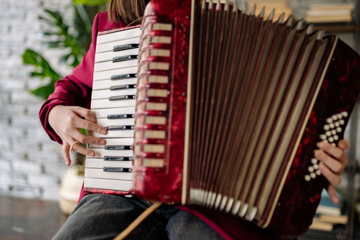 Close-up of a musician playing a piano accordion during a live traditional Irish music session indoors.