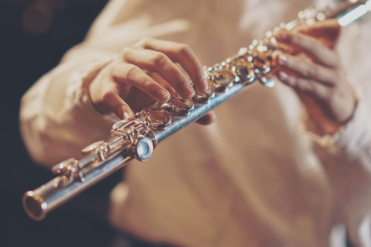 Close-up of a musician playing a silver flute during a live trad session in a dim pub