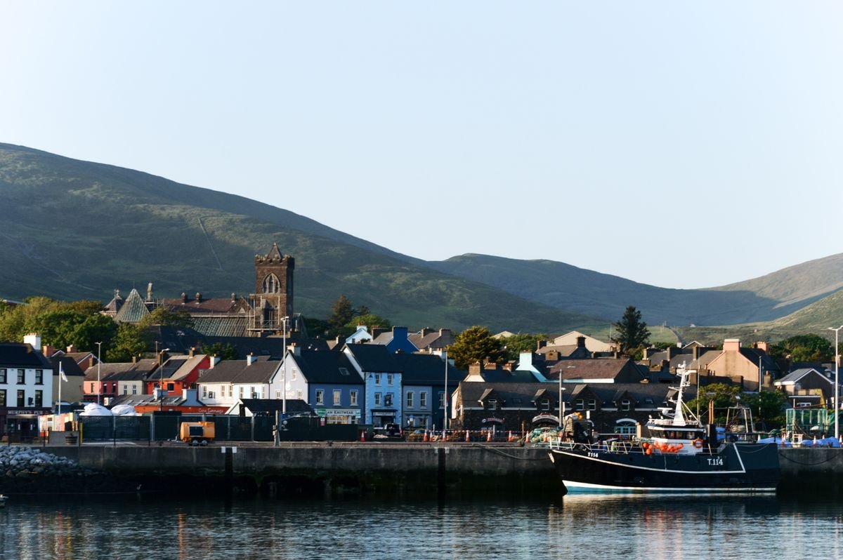Dingle town waterfront with colourful houses and a fishing boat in the harbour