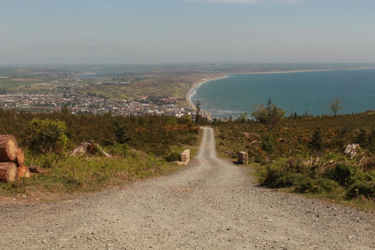 A rural road descending toward a coastal town in Northern Ireland