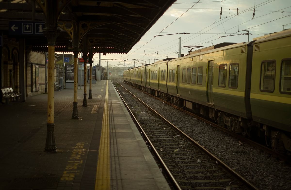 Green Irish Rail train at a station platform at dawn