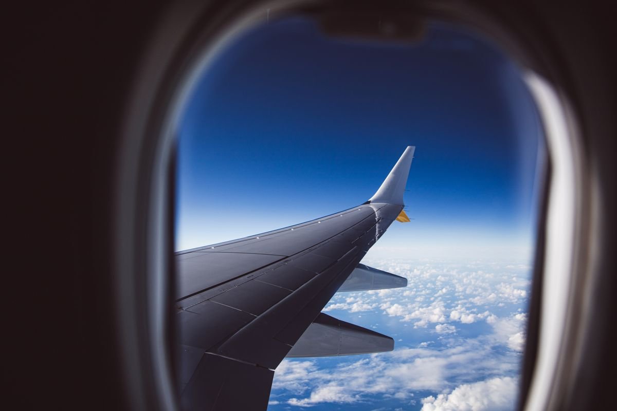 Airplane wing seen through a window above the clouds
