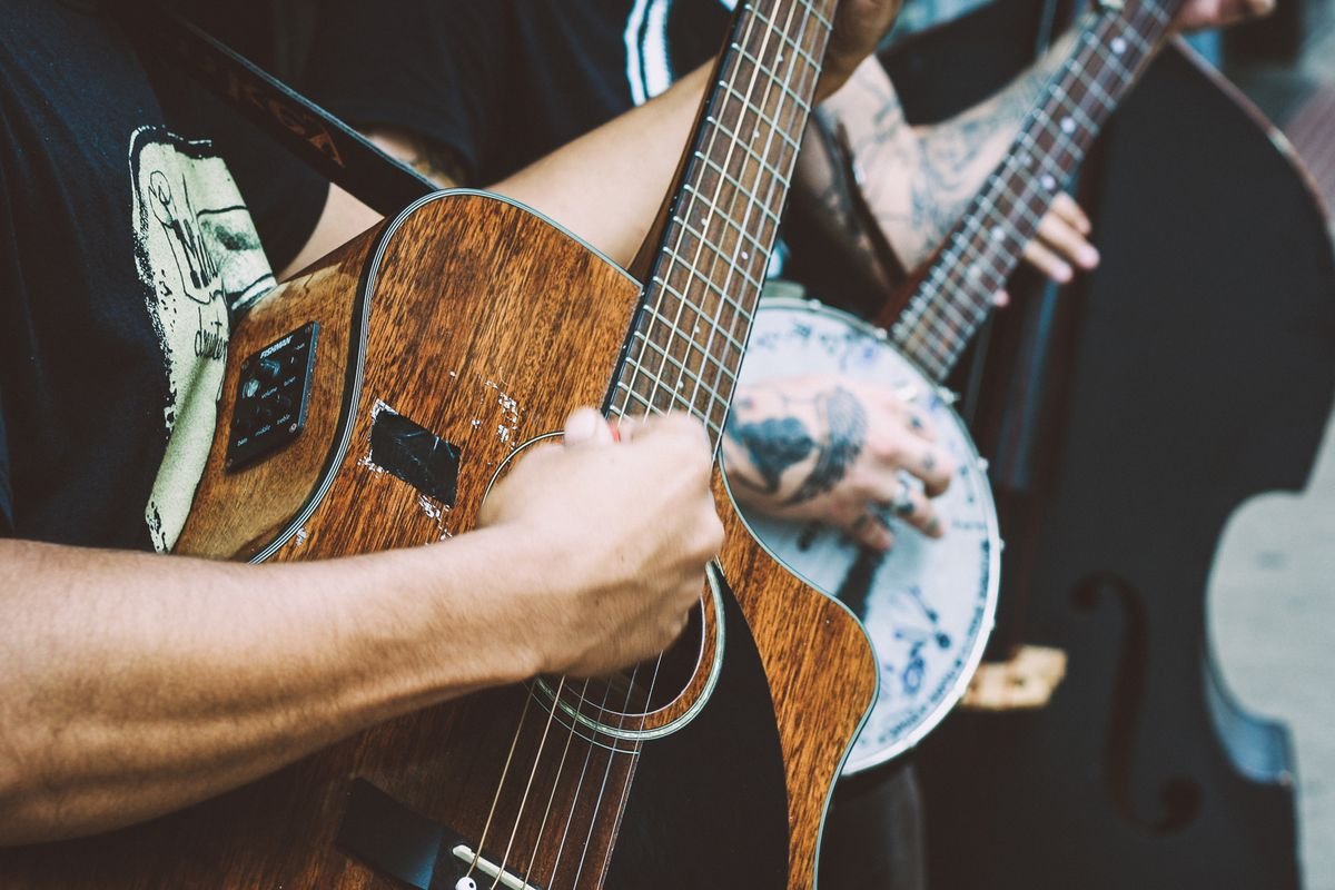 Close-up of hands strumming an acoustic guitar with a banjo player alongside during a live Irish trad session