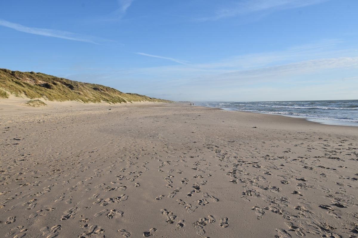 A wide empty sandy beach in Ireland running off toward the dunes and the sea.