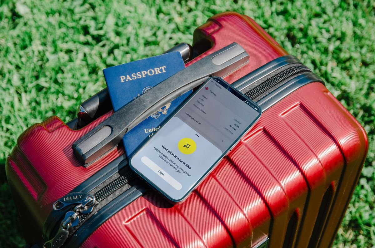 A passport and phone resting on a red suitcase