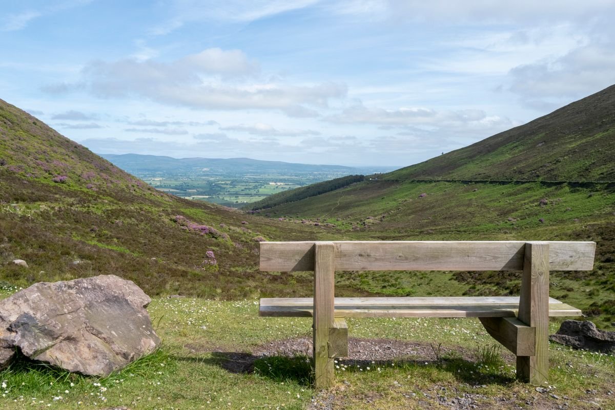 A bench at the top of an Irish hill walk looking over a green valley