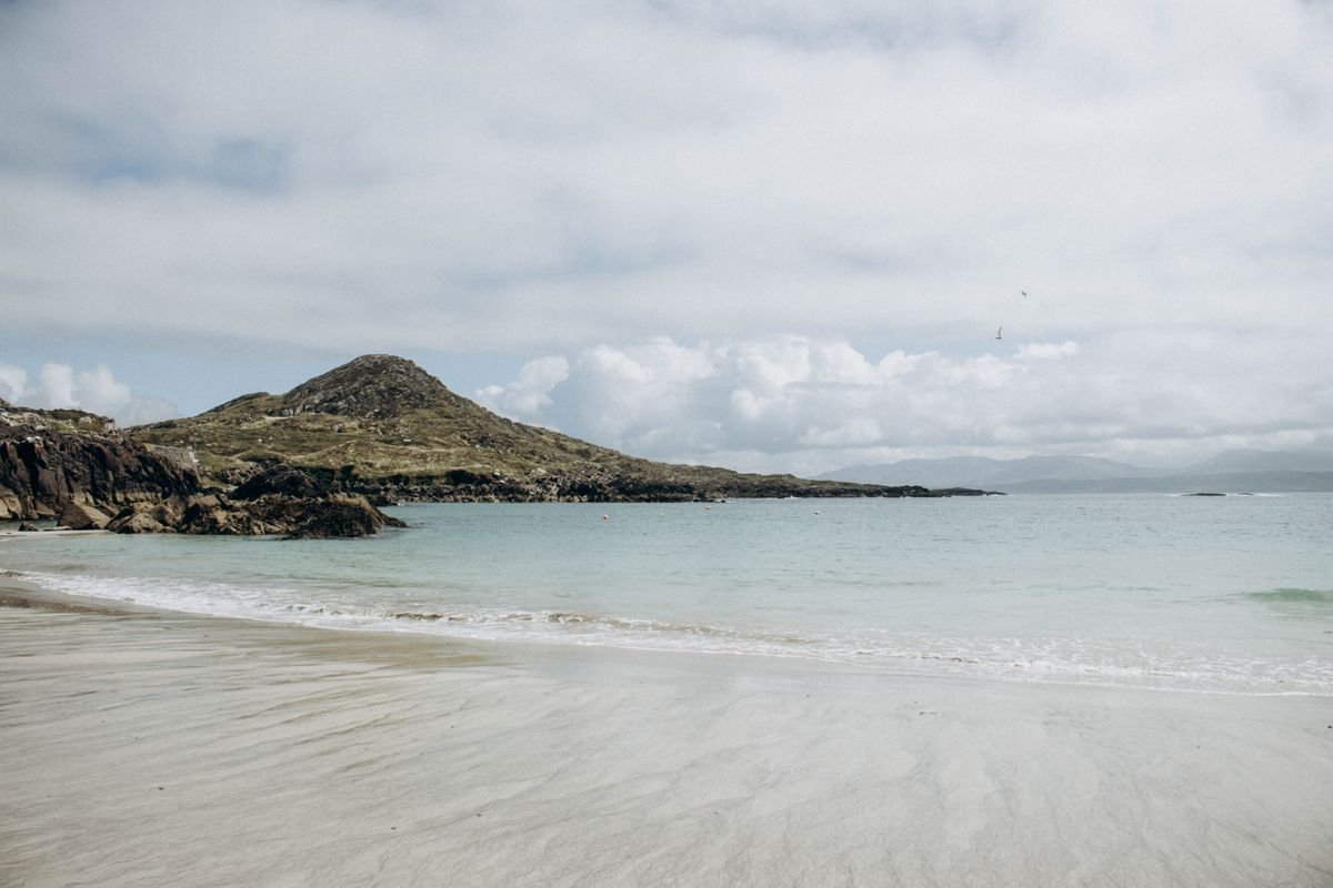 White curved sand bay with clear green water and a green headland at Dog's Bay near Roundstone.