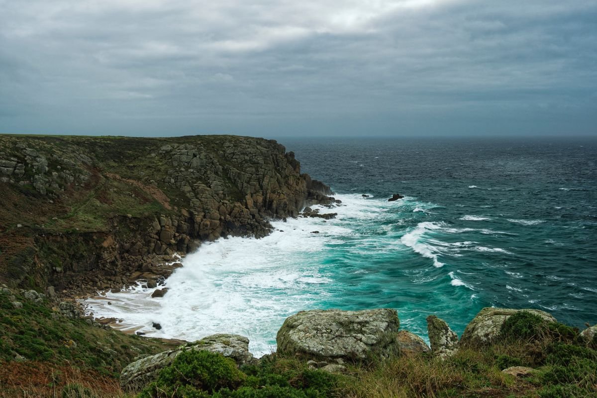 A rugged Irish headland with surf below under a grey sky