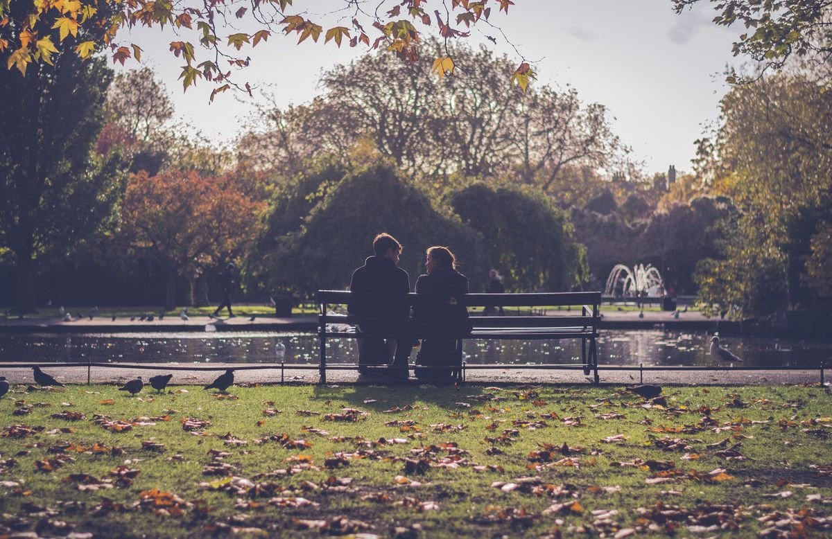 Couple on a bench by a park pond in early autumn in Dublin in September