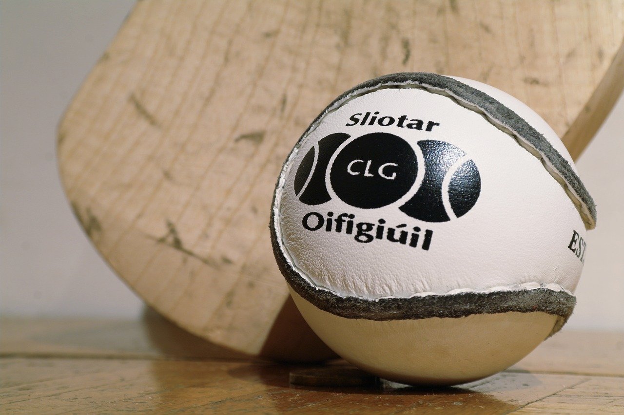 A hurling sliotar resting against a wooden hurl