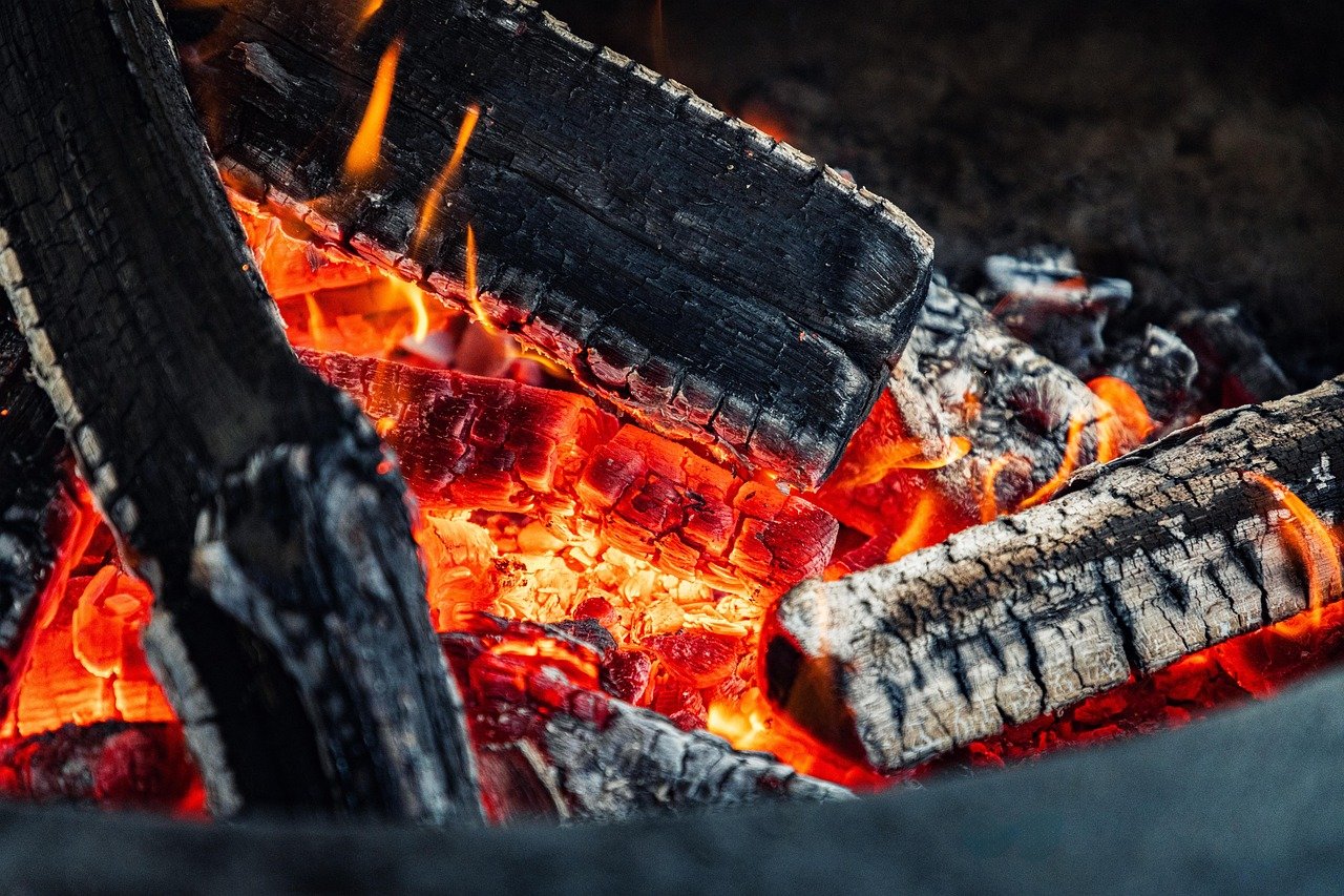 Close-up of glowing embers and burning logs in an open pub fire