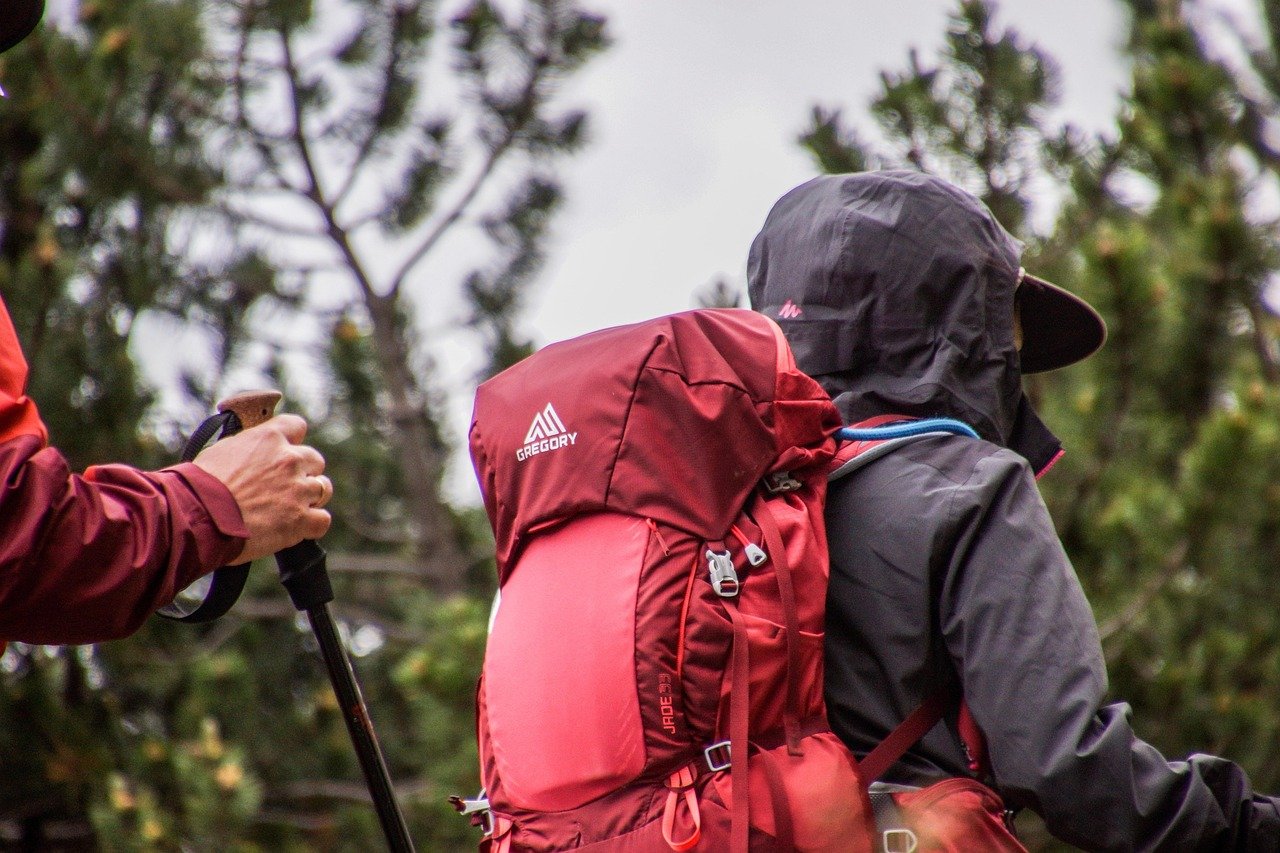 Hikers in waterproofs and rain hoods on an exposed trail under a grey sky