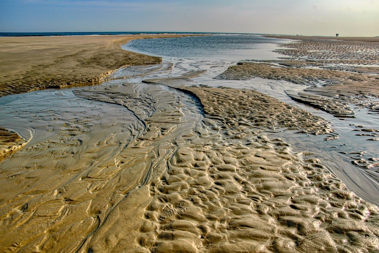 Wet tidal sand flats with shallow water channels draining at low tide on Omey Strand in Connemara.