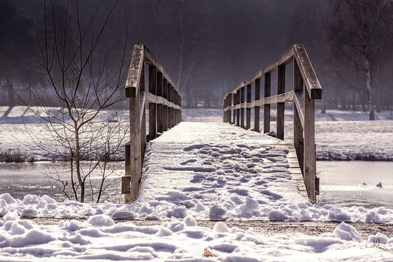 A frosty wooden footbridge over a partly frozen river in winter
