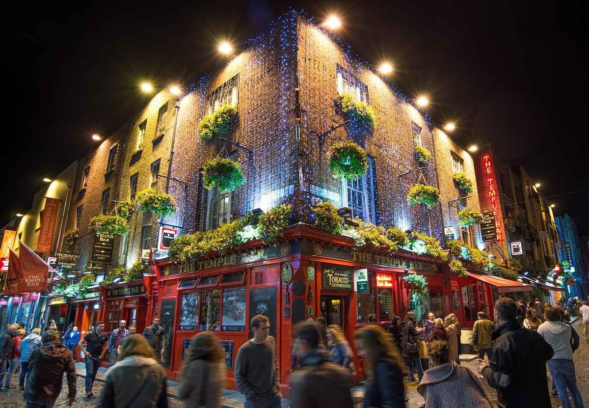 The Temple Bar pub in Dublin lit up at night with crowds