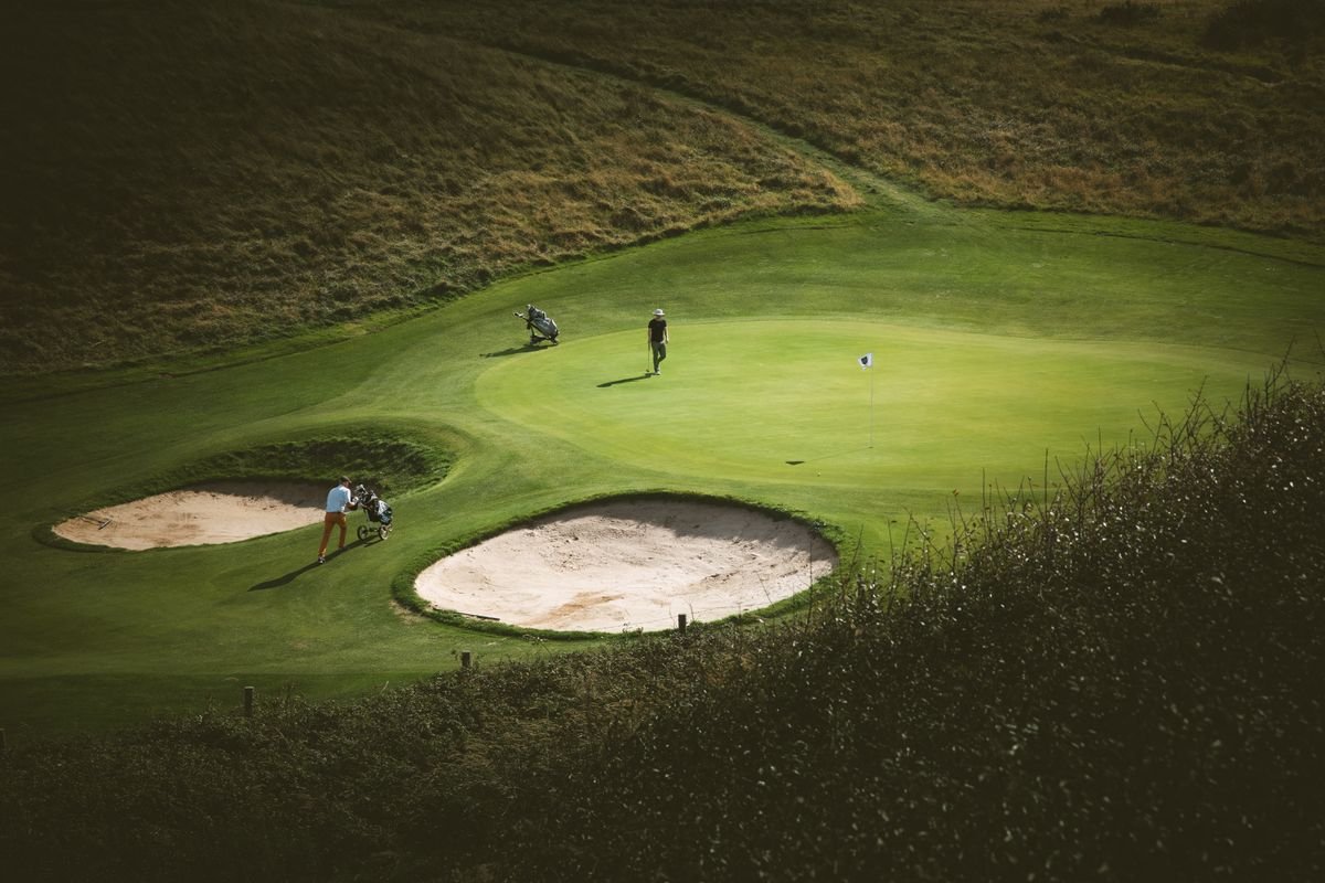 Two golfers on a coastal links green in Ireland