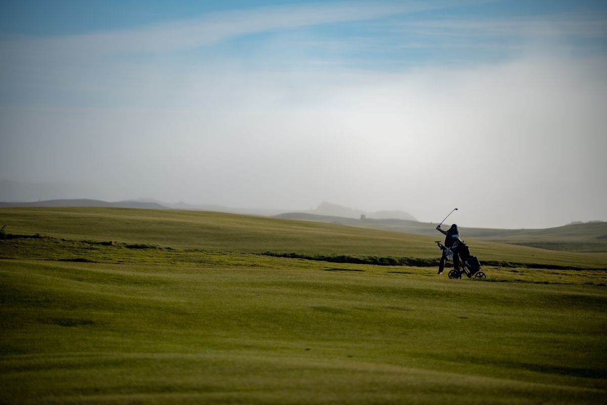 A golfer walking an Irish links course in soft light
