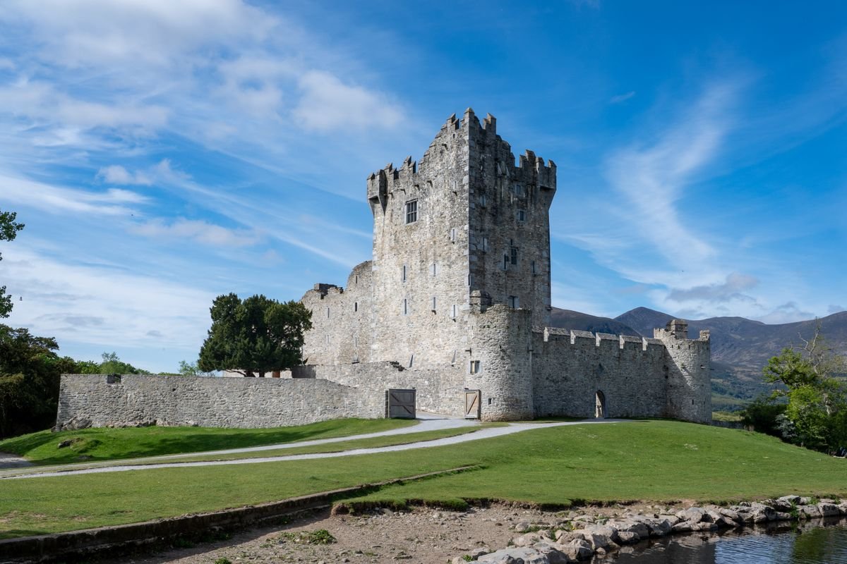Ross Castle tower house beside Lough Leane under a blue sky in Killarney National Park