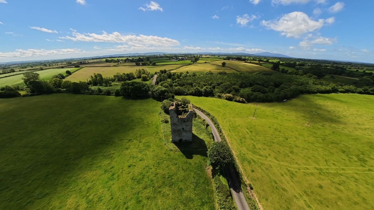 A lone Norman tower house standing in green Tipperary farmland by a country lane
