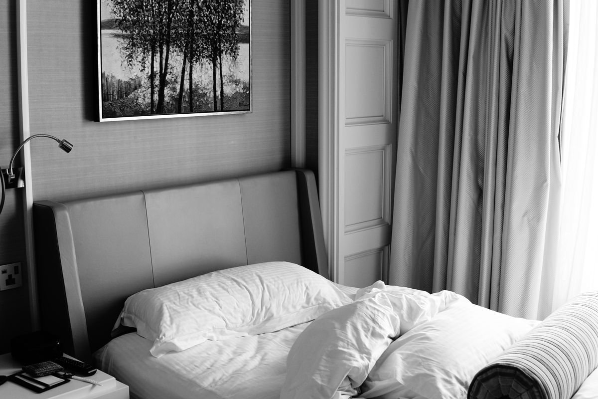 A made-up hotel bed with a framed picture above the headboard