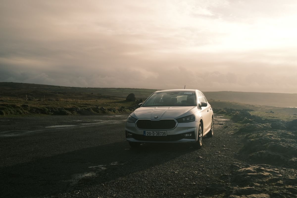 A hire car parked on a rural Irish road at sunset with an Irish registration plate