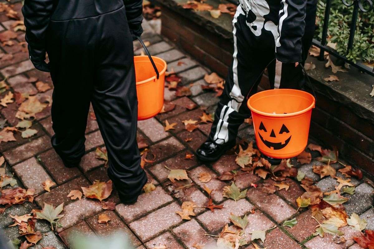 Kids in Halloween costumes carrying pumpkin trick or treat buckets