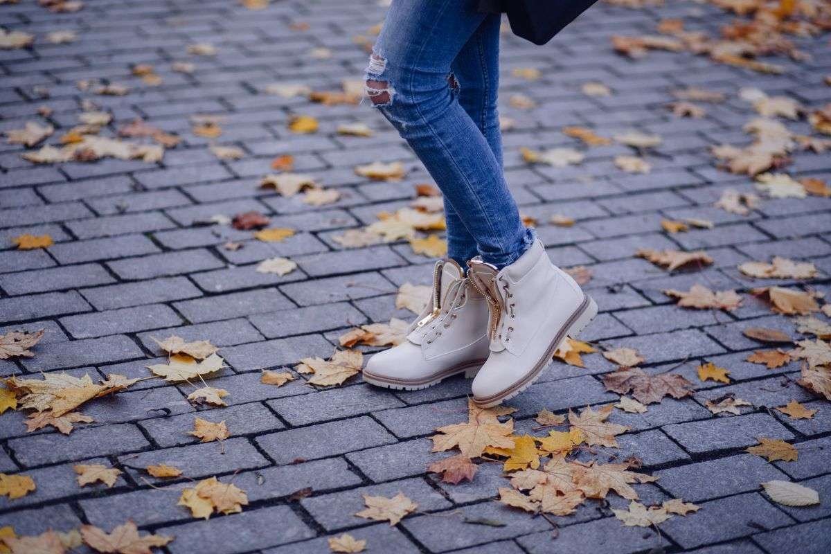 A pair of boots standing on cobblestones scattered with autumn leaves