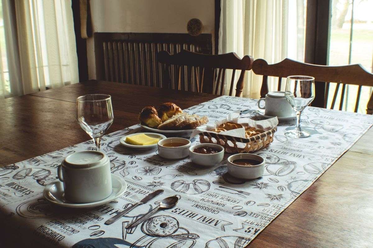 A B&B breakfast table with pastries, butter, jam and coffee by a window