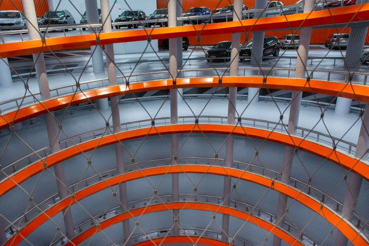 The interior of a multi story car park with parked cars and curved ramps