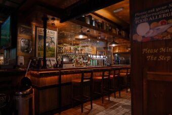 Dark wood interior of an old Dublin pub with a bar and stools