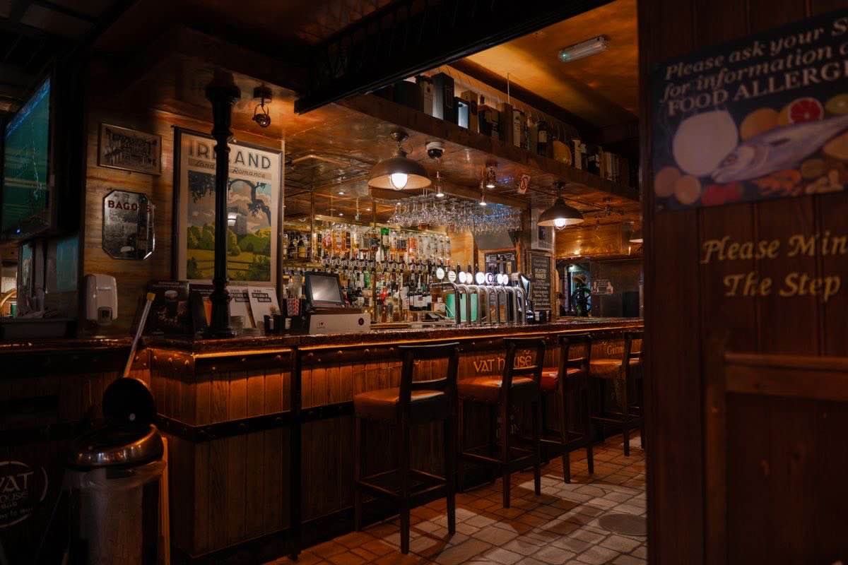 Dark wood interior of an old Dublin pub with a bar and stools