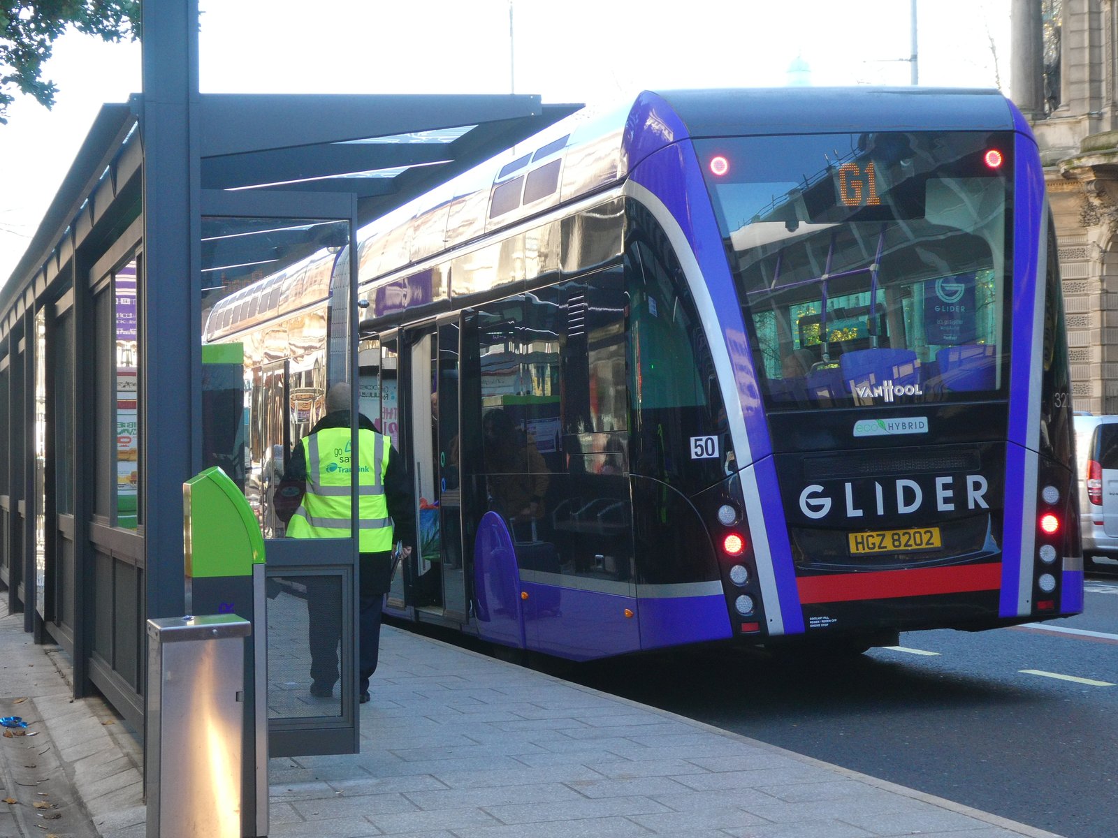 A purple Belfast Glider bus at a city stop
