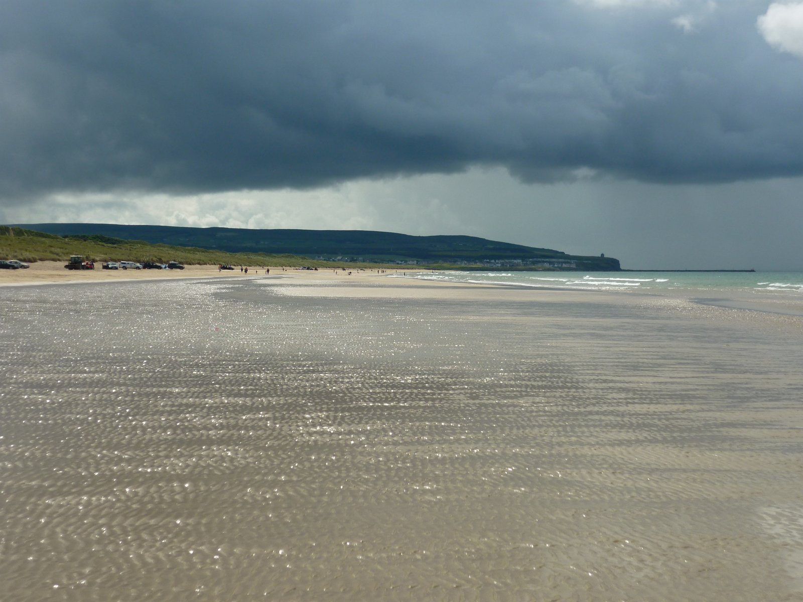 The wide golden sand of Portstewart Strand with cars parked near the dunes