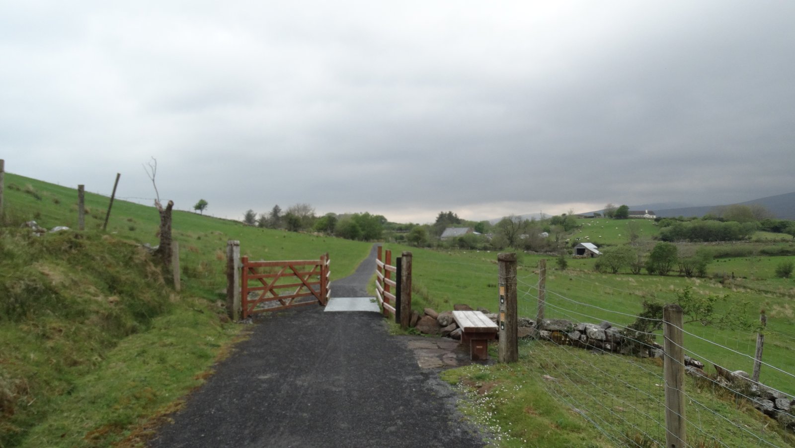 The Great Western Greenway path with a farm gate and stone wall in County Mayo
