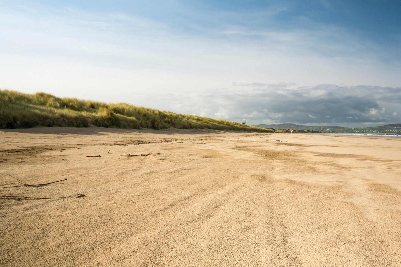 The wide flat sand of Benone Strand backed by dune grass