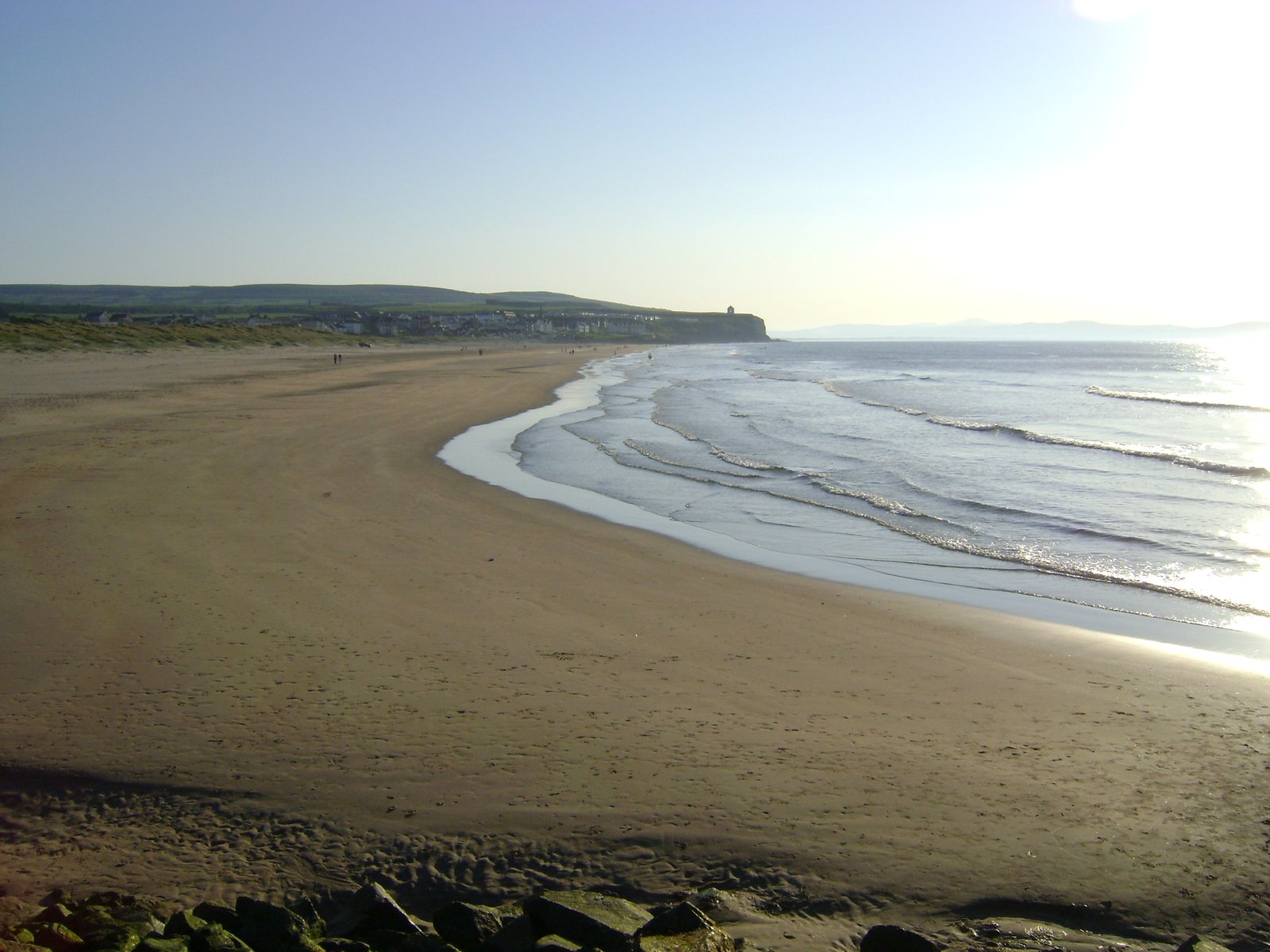 The wide golden sand of Castlerock Beach curving toward the village