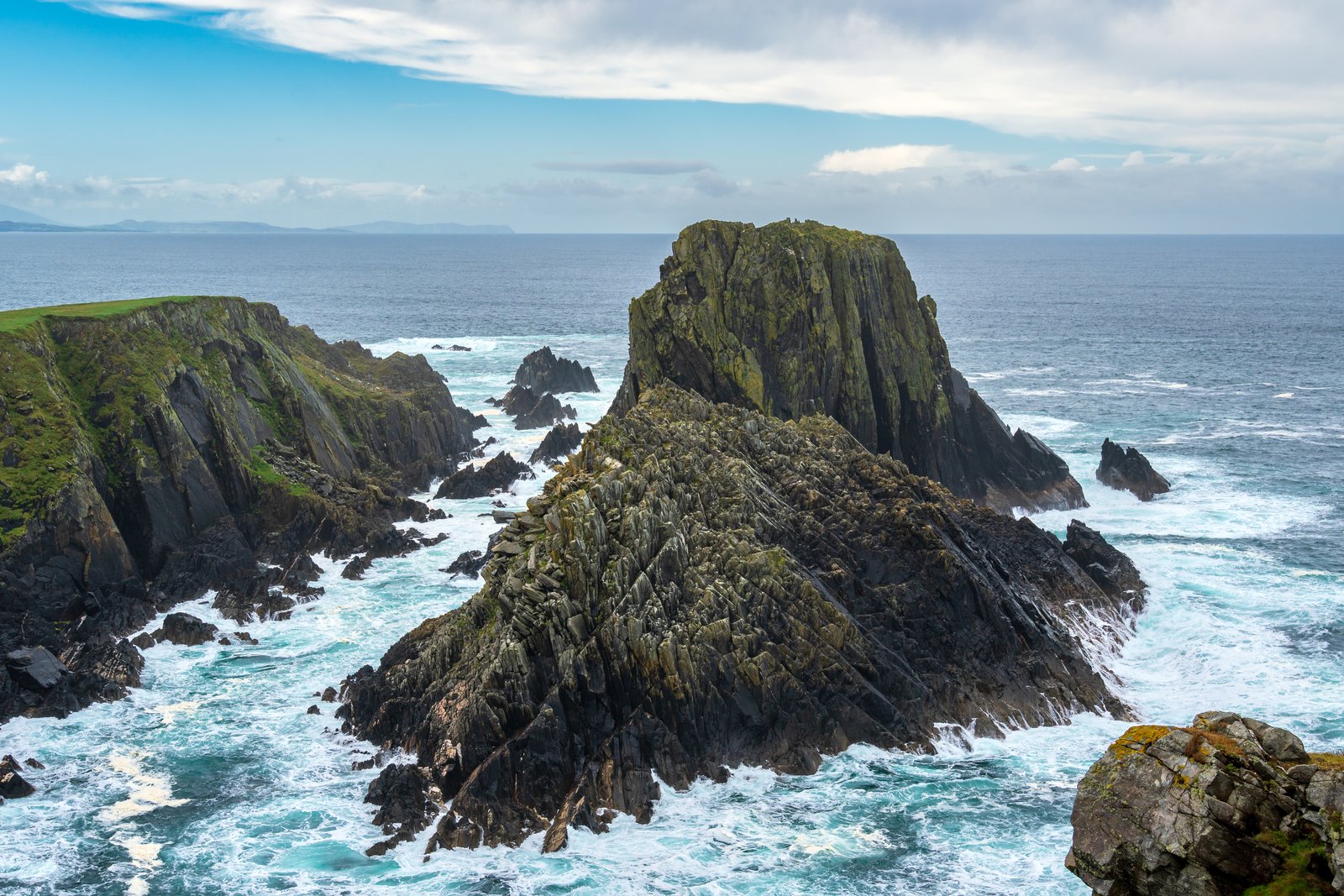 Jagged sea stacks and surf along the rocky coastline at Malin Head, County Donegal.