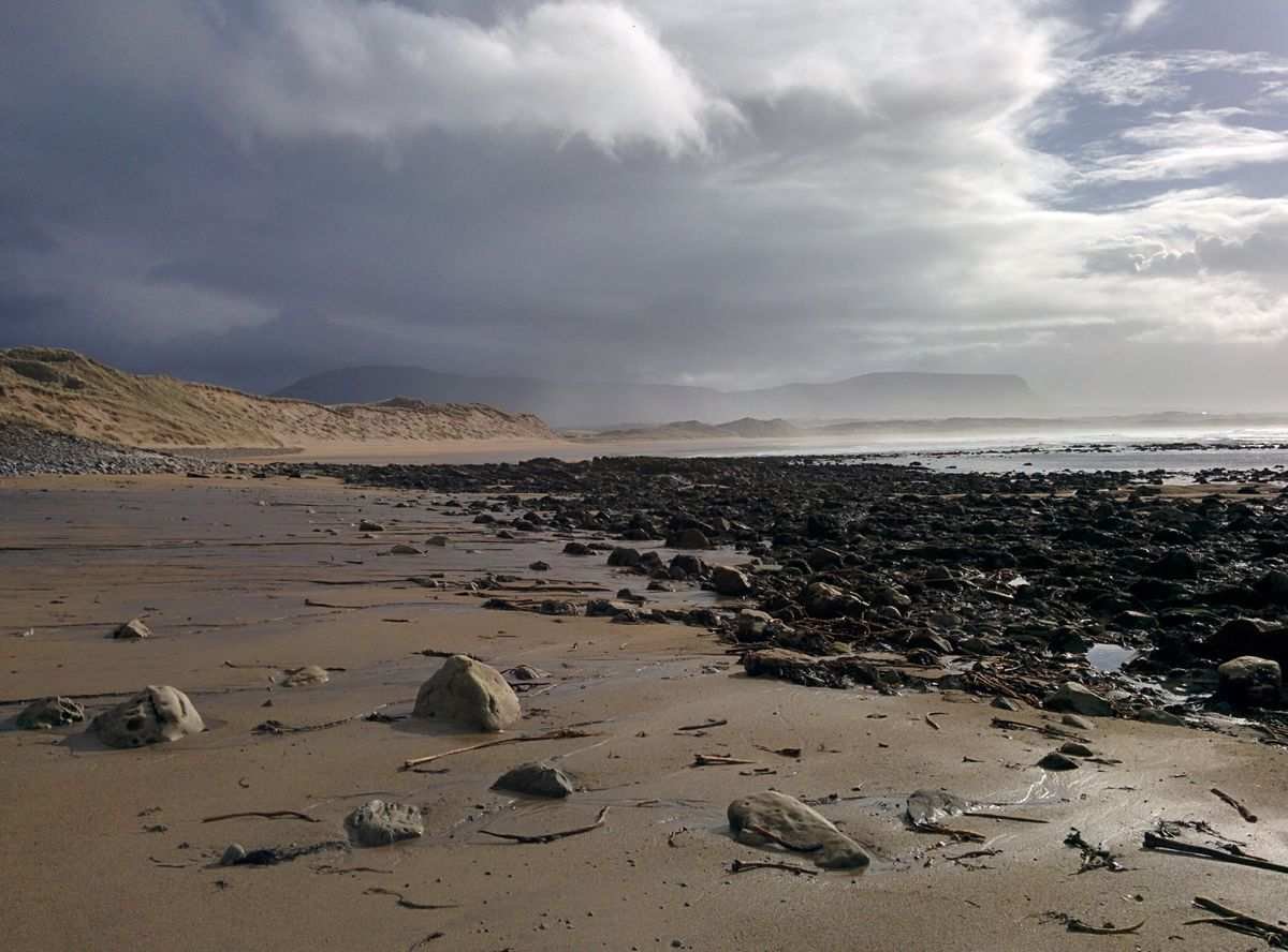 A rocky Sligo beach at low tide with a flat-topped mountain in the distance