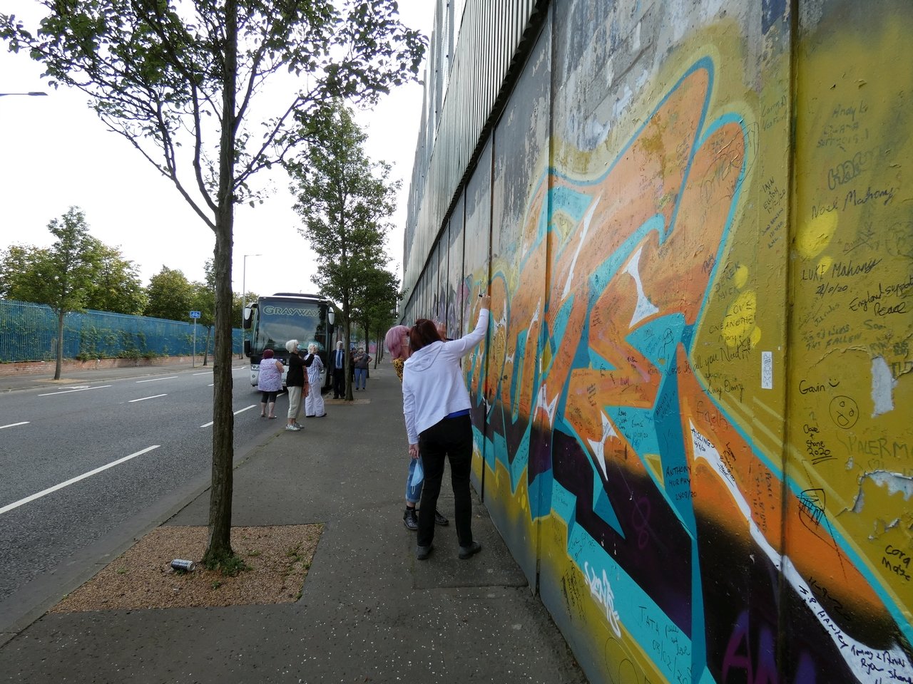 A visitor writing a message on the Belfast peace wall