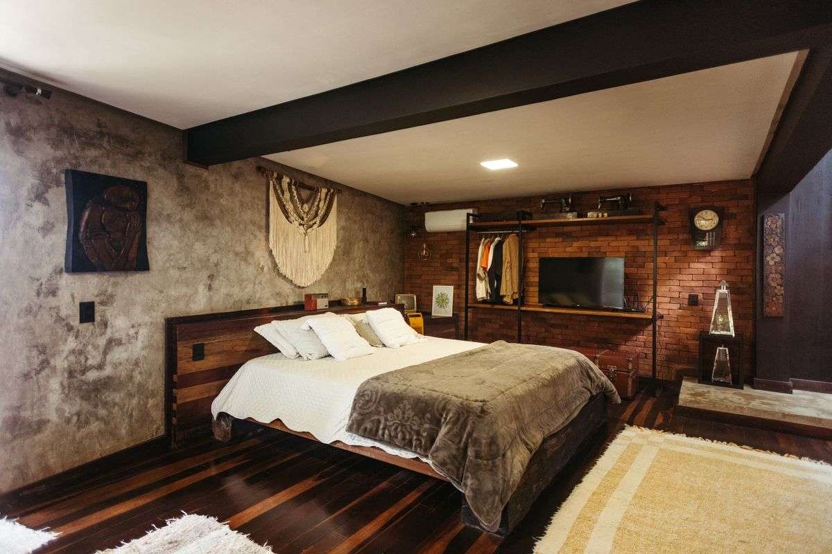 A warm bedroom interior with a made bed, wooden floor and brick wall