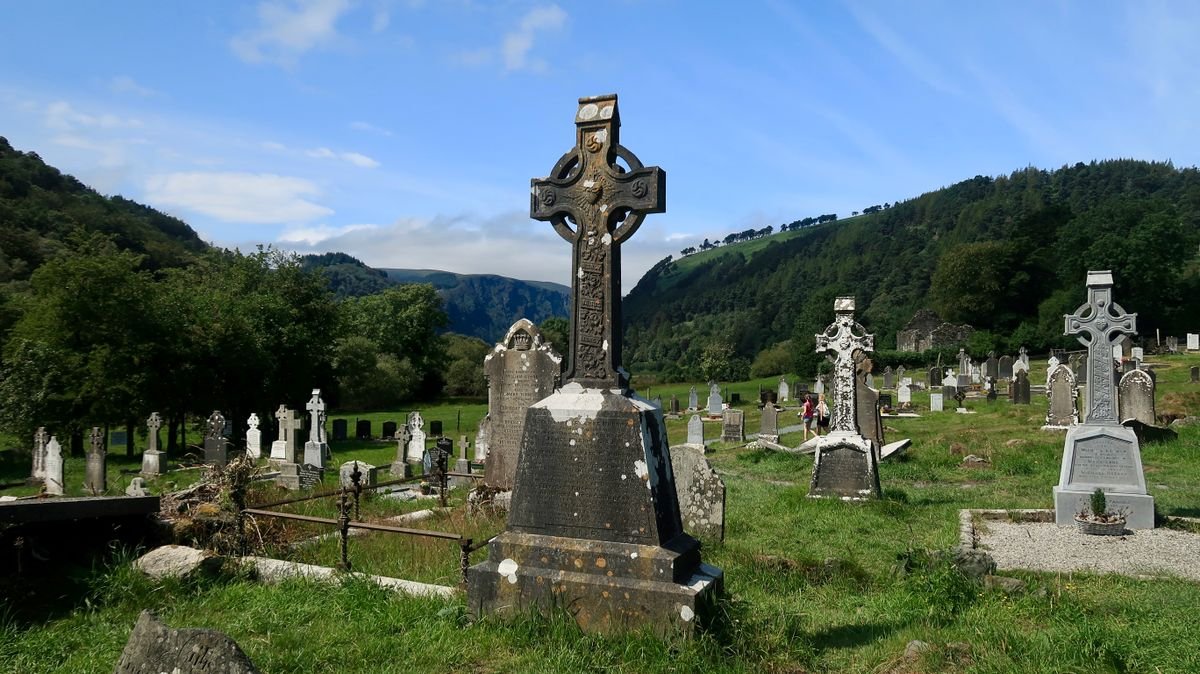 Weathered Celtic crosses in an old Irish graveyard with green hills behind