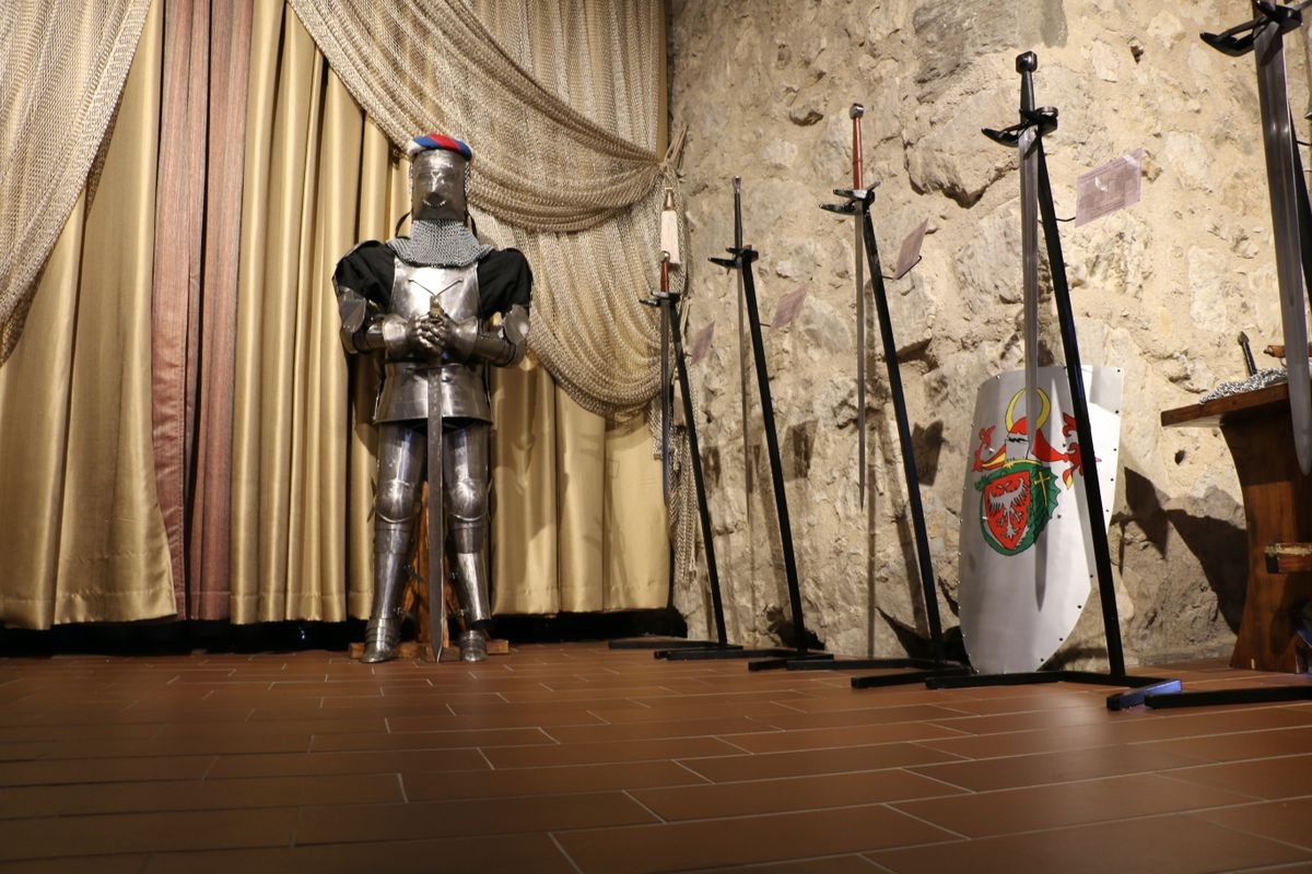 A suit of armour with swords and a shield on display