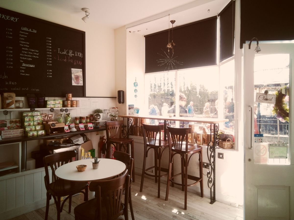 The interior of a small cafe with a chalkboard menu and window seats