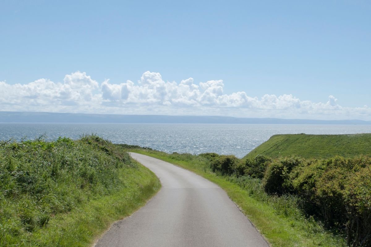 Narrow coastal road winding toward the sea in Northern Ireland
