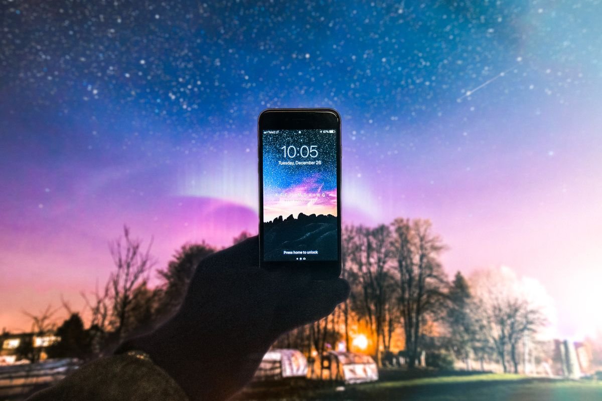 A hand holding a phone against a starry night sky