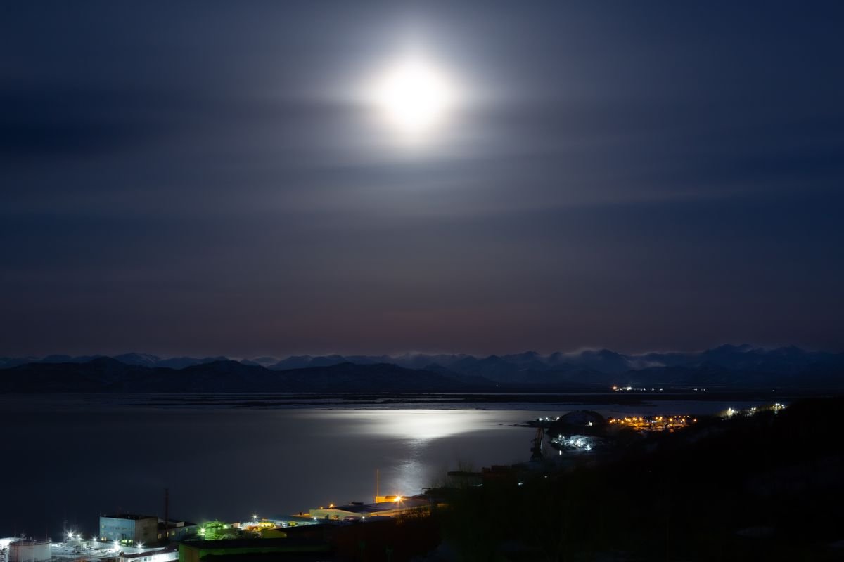 A lit town on the horizon of a dark night landscape
